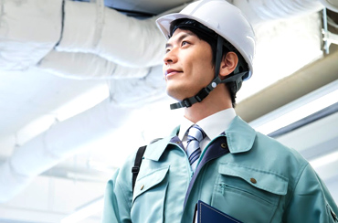 右上を見る作業着ヘルメット姿の男性